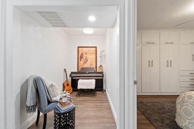 living area featuring visible vents, baseboards, and wood finished floors