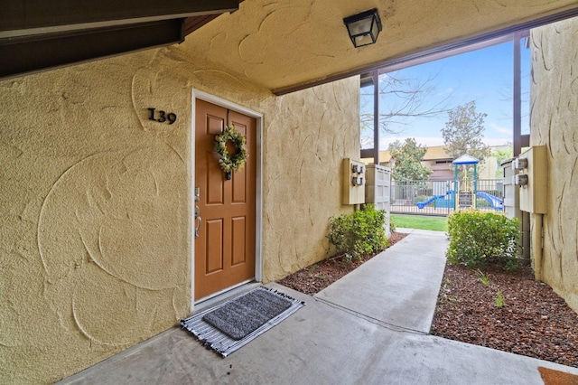 view of exterior entry featuring fence and stucco siding