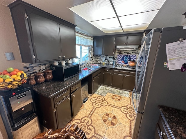 kitchen with decorative backsplash, dark stone counters, stainless steel appliances, and a sink