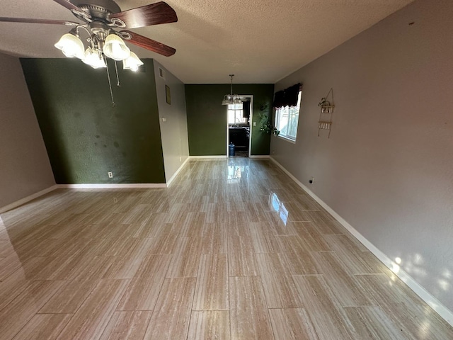 interior space featuring a textured ceiling, light wood finished floors, and baseboards