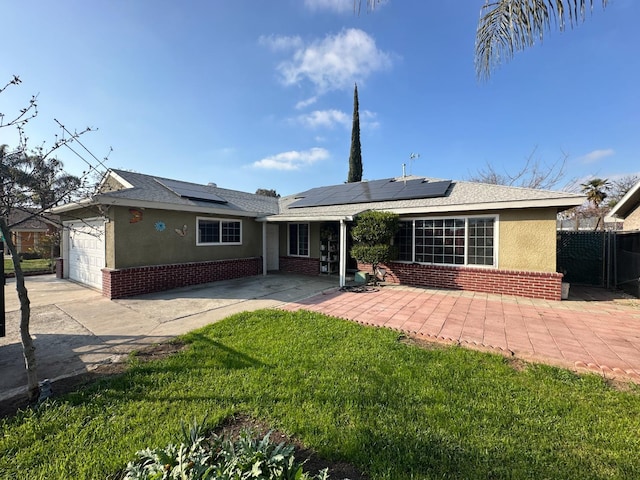 back of house featuring a garage, roof mounted solar panels, brick siding, and stucco siding