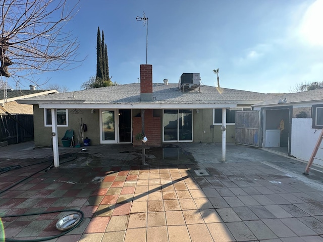 back of house featuring roof with shingles, a chimney, central air condition unit, a patio area, and fence