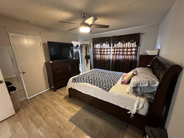 bedroom with a textured ceiling, a ceiling fan, a closet, and wood finish floors