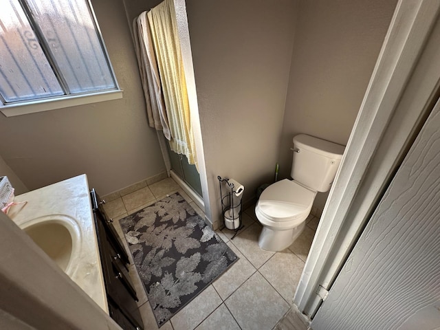 bathroom with tile patterned flooring, toilet, vanity, baseboards, and a stall shower