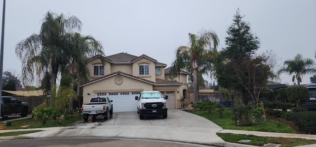 view of front of home featuring stucco siding, an attached garage, concrete driveway, and fence