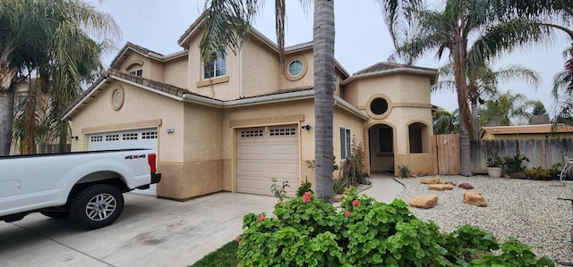 view of front of home with stucco siding, driveway, a garage, and fence