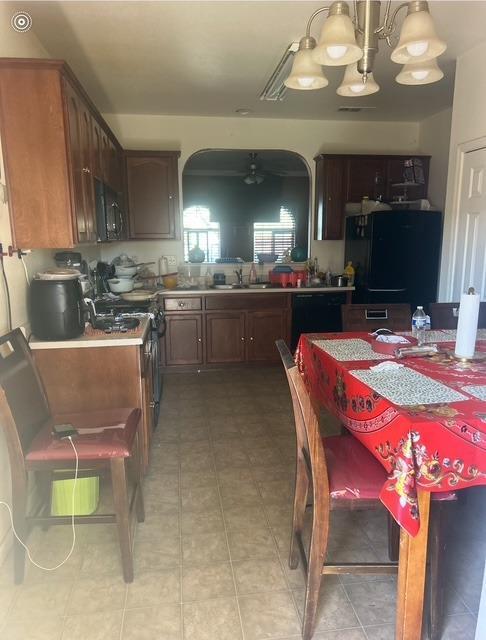 kitchen featuring a notable chandelier, a sink, black appliances, and light tile patterned floors