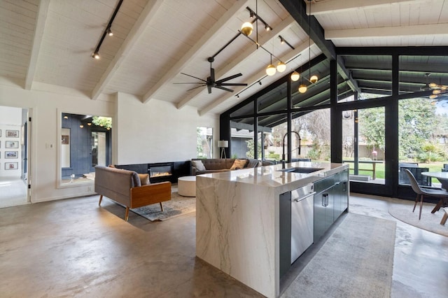 kitchen featuring stainless steel dishwasher, a glass covered fireplace, a sink, modern cabinets, and concrete flooring