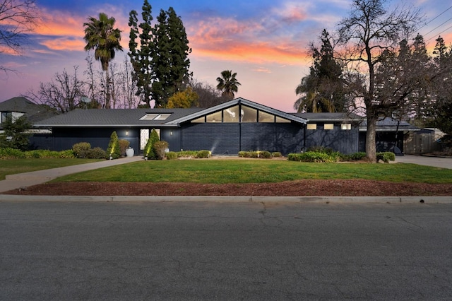 mid-century home featuring driveway and a front lawn