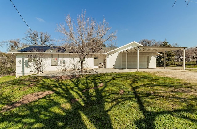 view of front facade featuring driveway, stucco siding, roof mounted solar panels, a carport, and a front yard