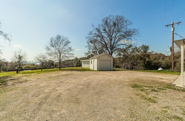 view of yard with driveway, an outdoor structure, and a detached garage