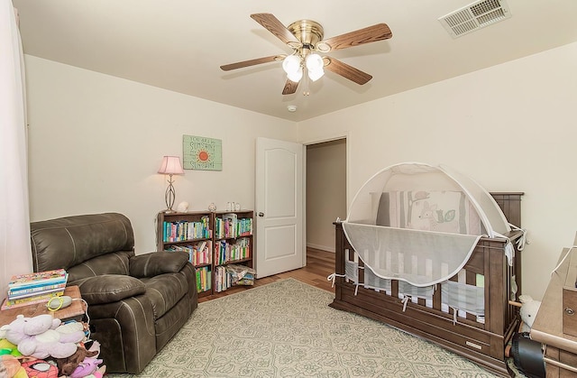 interior space with a ceiling fan, visible vents, and wood finished floors