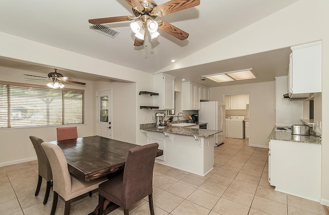 dining space with light tile patterned floors, baseboards, visible vents, lofted ceiling, and independent washer and dryer