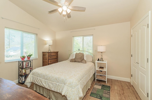 bedroom featuring light wood-style floors, multiple windows, vaulted ceiling, and baseboards