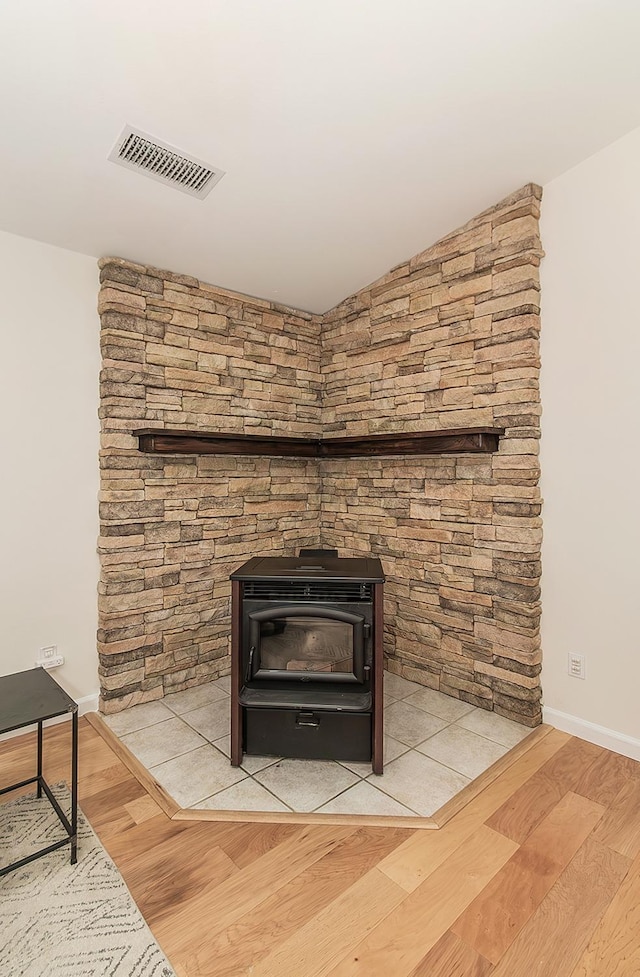 room details with a wood stove, wood finished floors, and visible vents