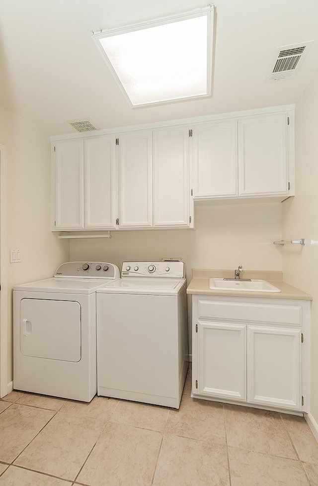 clothes washing area featuring cabinet space, light tile patterned floors, visible vents, separate washer and dryer, and a sink