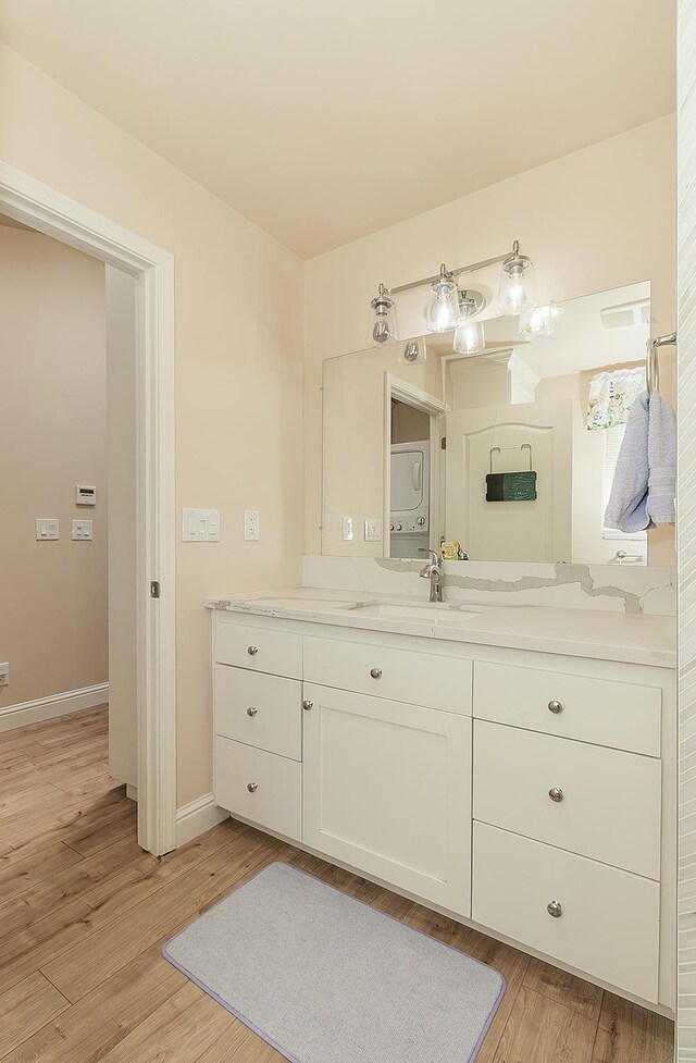 29039 Auberry Rd, Prather, CA 93651 - bathroom featuring vanity, wood finished floors, baseboards, and estacked washer and dryer