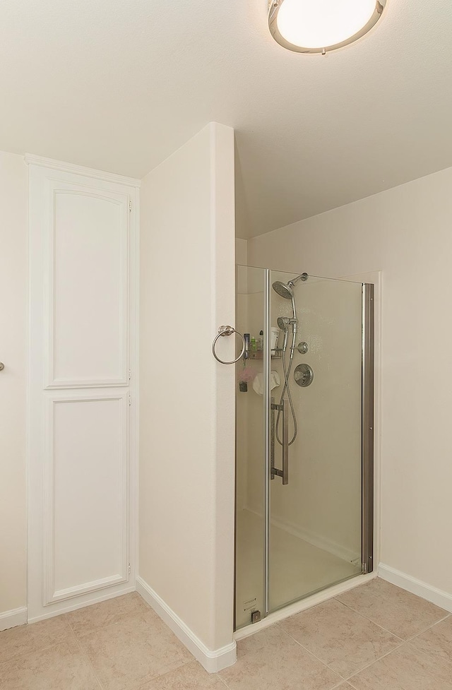 bathroom with baseboards, a shower stall, and tile patterned floors