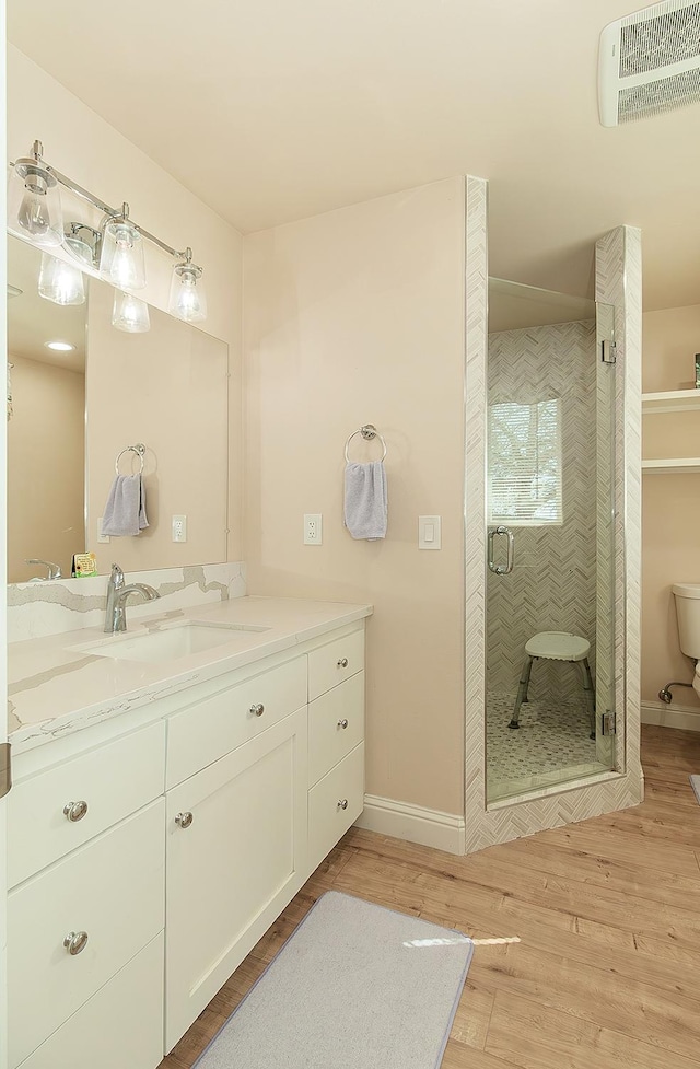 full bathroom featuring a stall shower, baseboards, visible vents, wood finished floors, and vanity