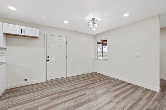 empty room featuring light wood finished floors, recessed lighting, and baseboards