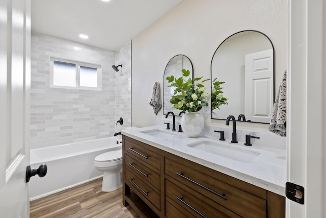 full bath with double vanity, wood finished floors, a sink, and toilet