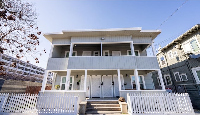 view of front of property featuring a porch, fence, and a balcony