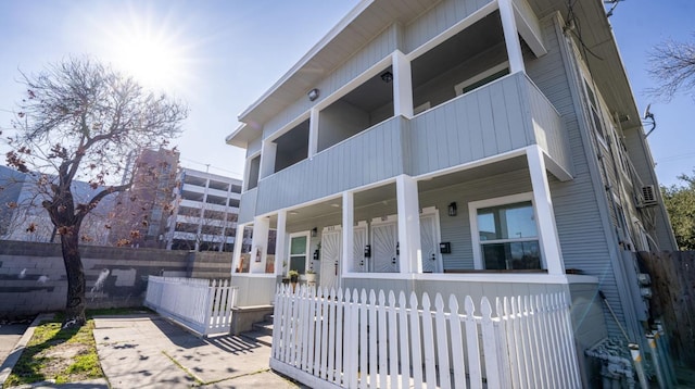 view of front of house with a balcony, covered porch, and a fenced front yard