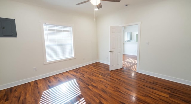 empty room with ceiling fan, wood finished floors, electric panel, and baseboards