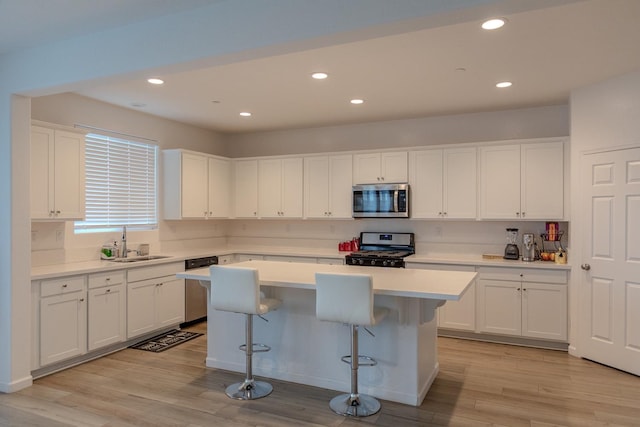 kitchen with white cabinetry, stainless steel appliances, a sink, and a center island