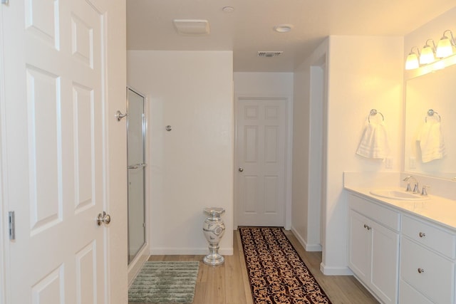 bathroom featuring vanity, wood finished floors, visible vents, and a shower stall