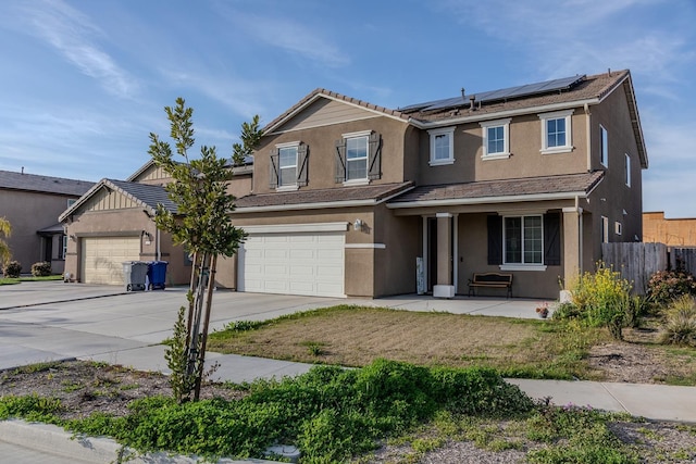 traditional home with a garage, concrete driveway, fence, roof mounted solar panels, and stucco siding