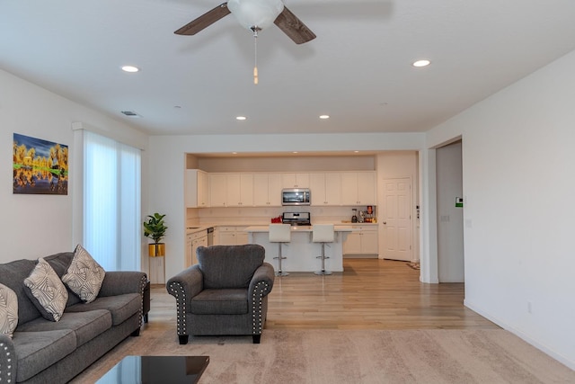 living room with recessed lighting, visible vents, light wood-style floors, ceiling fan, and baseboards