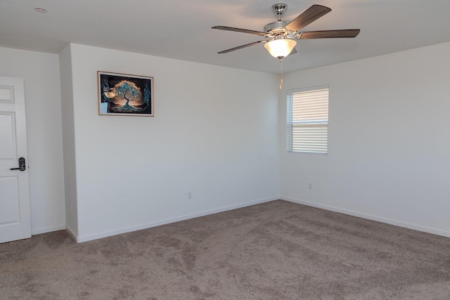 carpeted spare room with a ceiling fan and baseboards