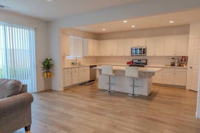 kitchen featuring white cabinets, light wood-style flooring, stainless steel appliances, and light countertops