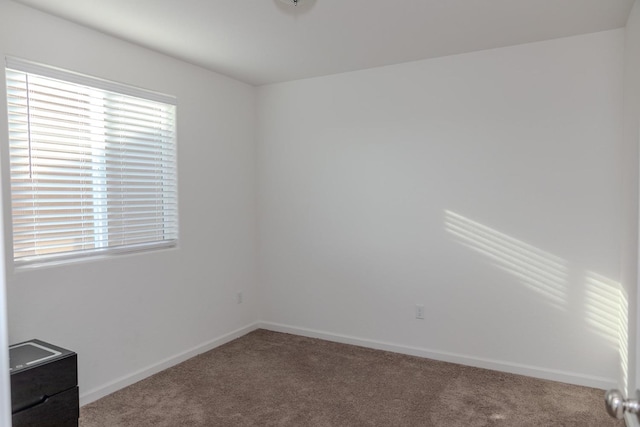 spare room featuring carpet flooring and baseboards