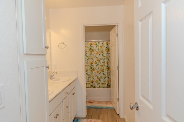 bathroom with double vanity, wood finished floors, a sink, and shower / bathtub combination with curtain