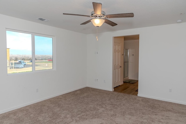 unfurnished room featuring carpet floors, baseboards, visible vents, and ceiling fan