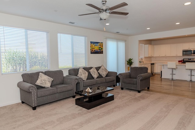 living area with light wood finished floors, a ceiling fan, visible vents, and recessed lighting