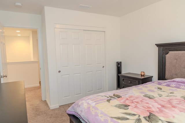 bedroom with light carpet, a closet, visible vents, and baseboards