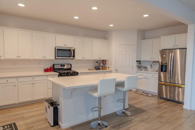 kitchen featuring light wood-style flooring, white cabinetry, stainless steel appliances, and light countertops