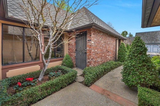 entrance to property with brick siding and roof with shingles