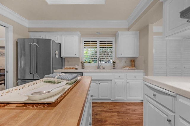 kitchen with high end refrigerator, white cabinets, and crown molding