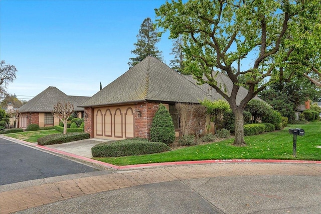 view of front facade featuring an attached garage, brick siding, a shingled roof, driveway, and a front lawn