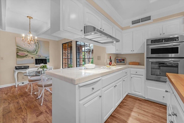 kitchen with white stovetop, visible vents, double oven, a peninsula, and under cabinet range hood