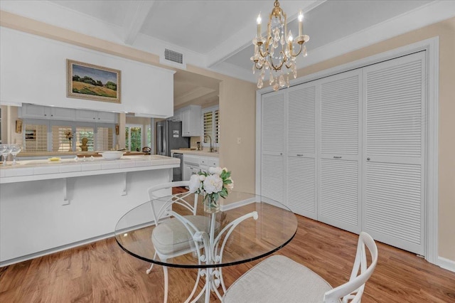 dining room featuring beam ceiling, visible vents, a chandelier, light wood-type flooring, and baseboards