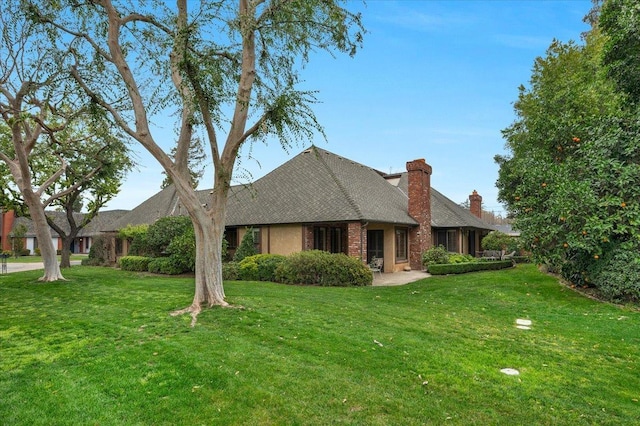 view of front of house featuring a front lawn, a chimney, and brick siding