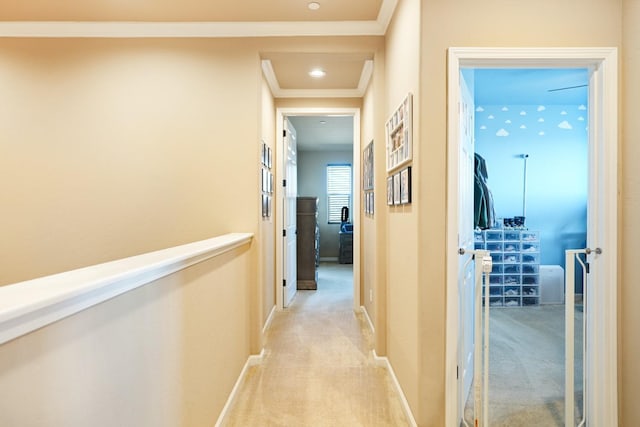 corridor with baseboards, crown molding, and light colored carpet