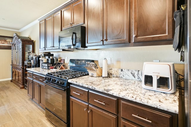 kitchen with light stone countertops, black appliances, light wood-type flooring, and crown molding