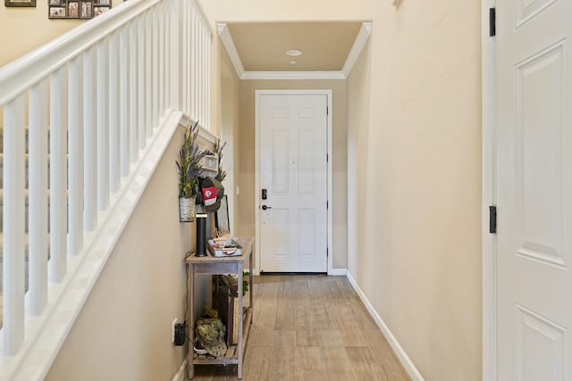 corridor with light wood finished floors, stairs, baseboards, and crown molding