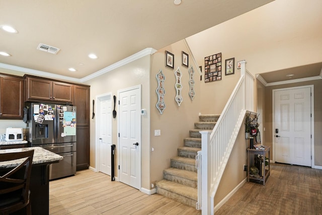 kitchen featuring dark brown cabinetry, visible vents, stainless steel fridge with ice dispenser, light wood-style flooring, and crown molding